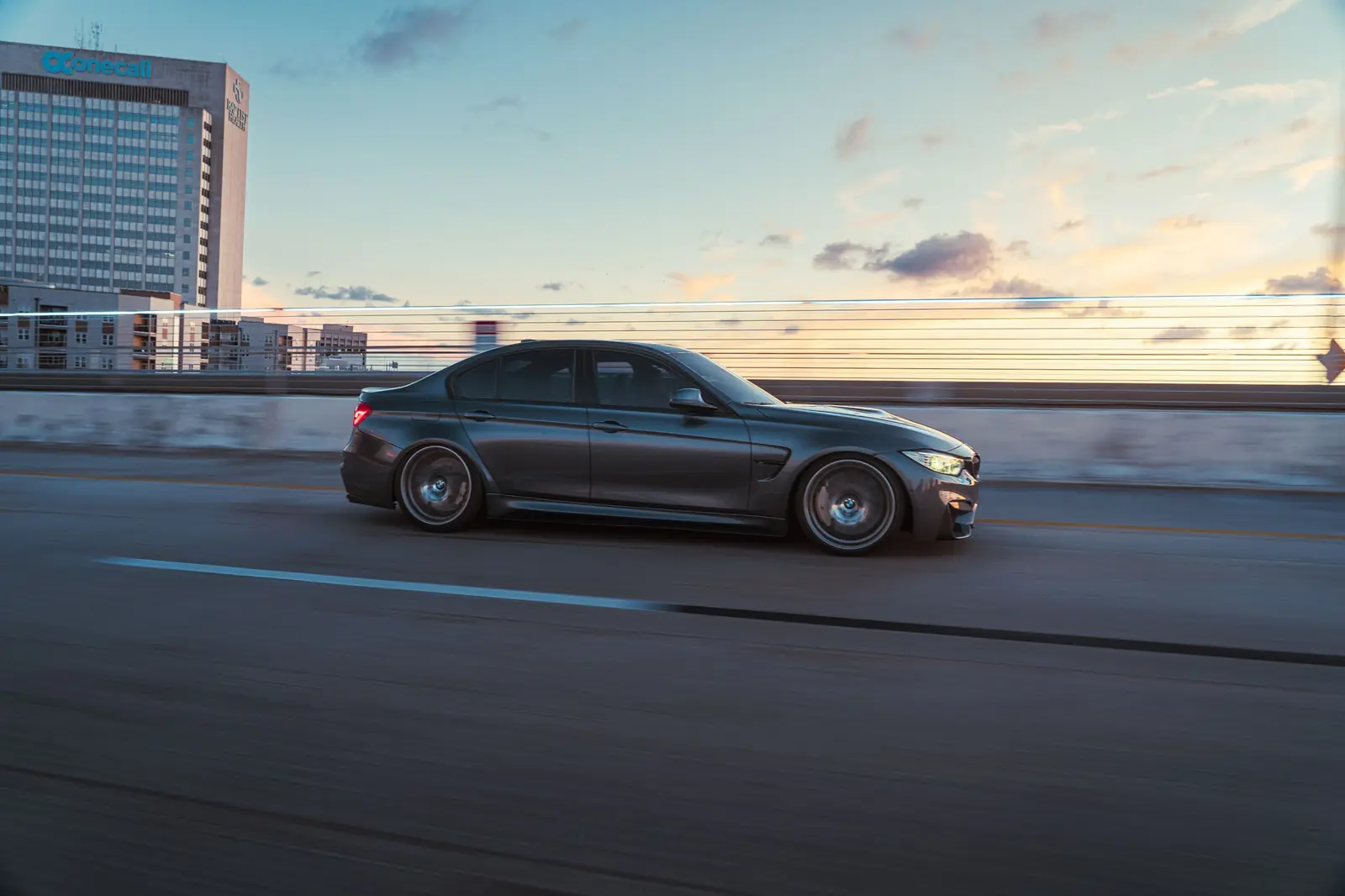 Dark sedan driving on a Miami highway at dusk with the skyline behind