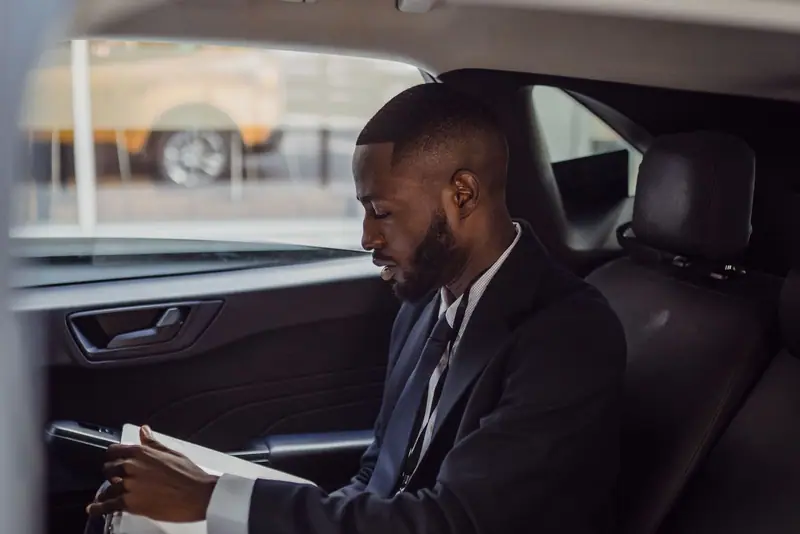Businessman reading in the back seat of a car