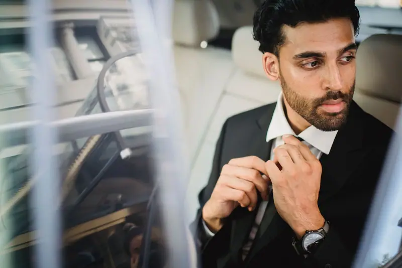 Businessman adjusting his tie in the back of a car