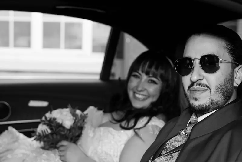 Couple smiling in the back of a car in black and white