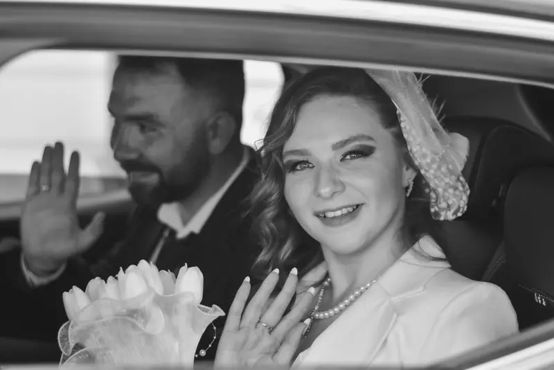 Bride and groom waving from a car