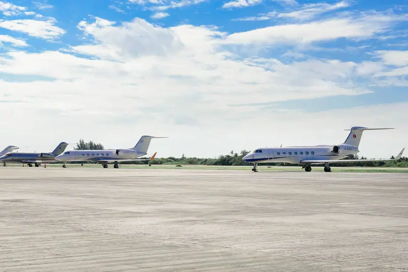Private jets parked on a runway under a blue sky