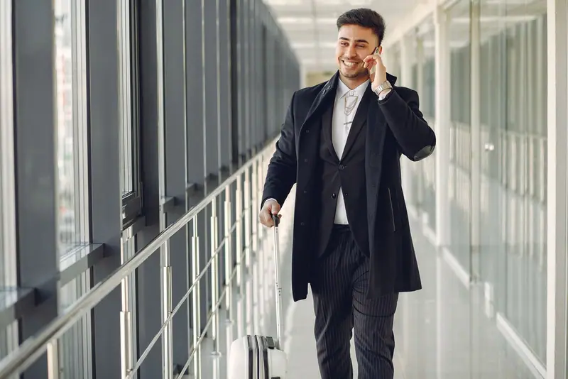Businessman on the phone walking with his luggage