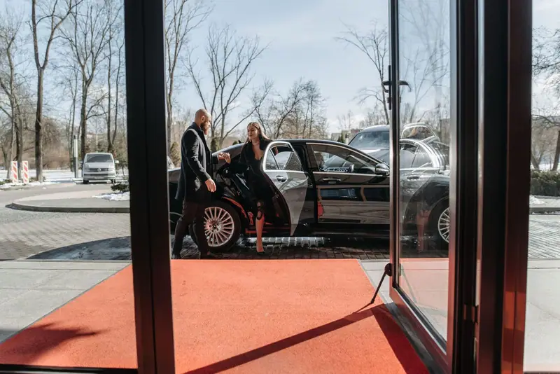 Black car pulling up to a hotel entrance with a red carpet