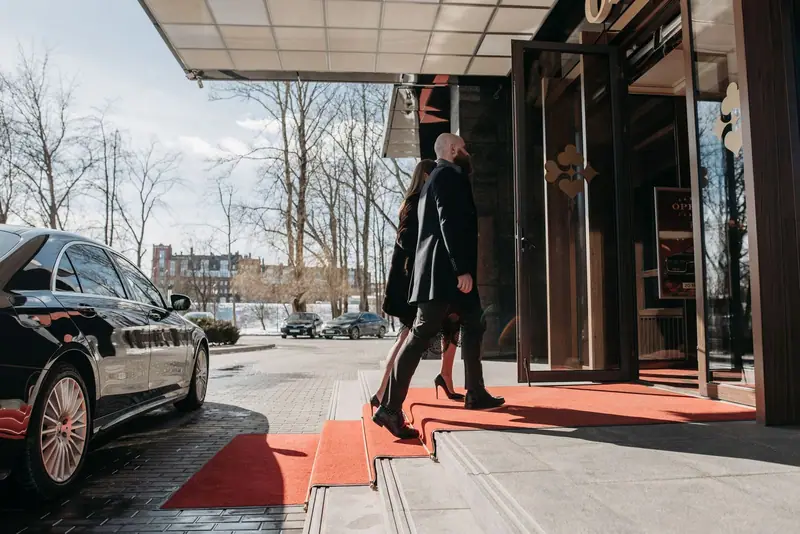 Black limousine at a hotel entrance with a guest on the red carpet