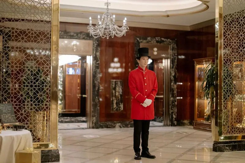 Hotel doorman in a red uniform in an ornate lobby
