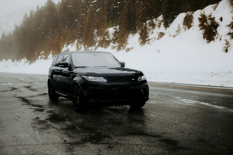 Black Range Rover on a wet road in winter