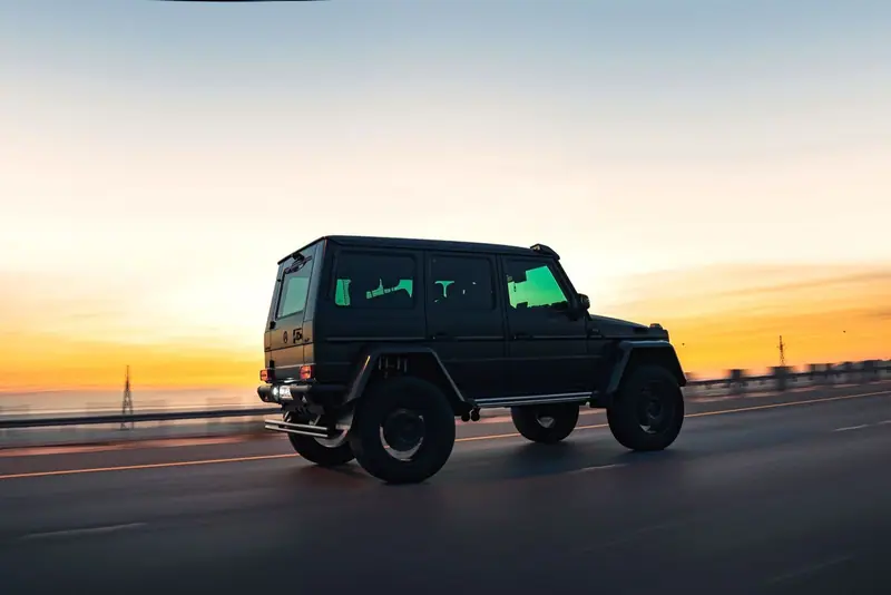 Black Mercedes G-Class on a road at sunset