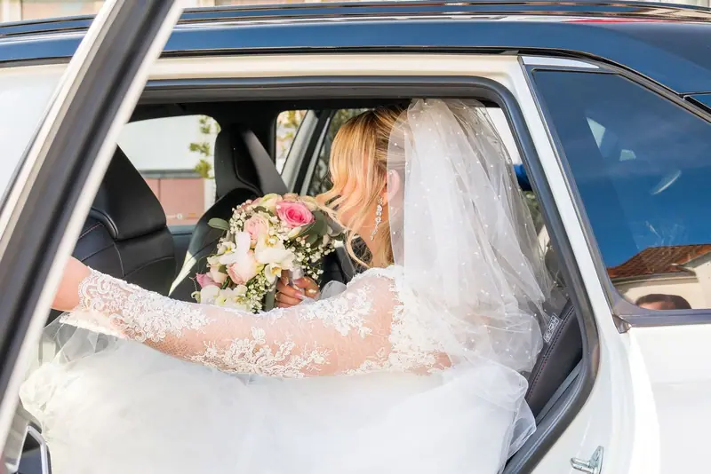 Bride in a white car looking at her bouquet