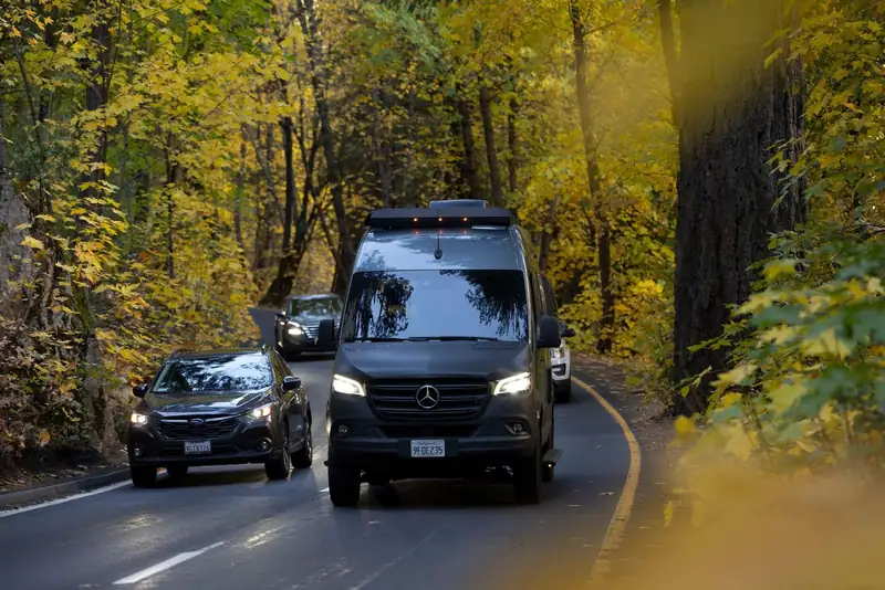 Black Sprinter van driving along a forest road