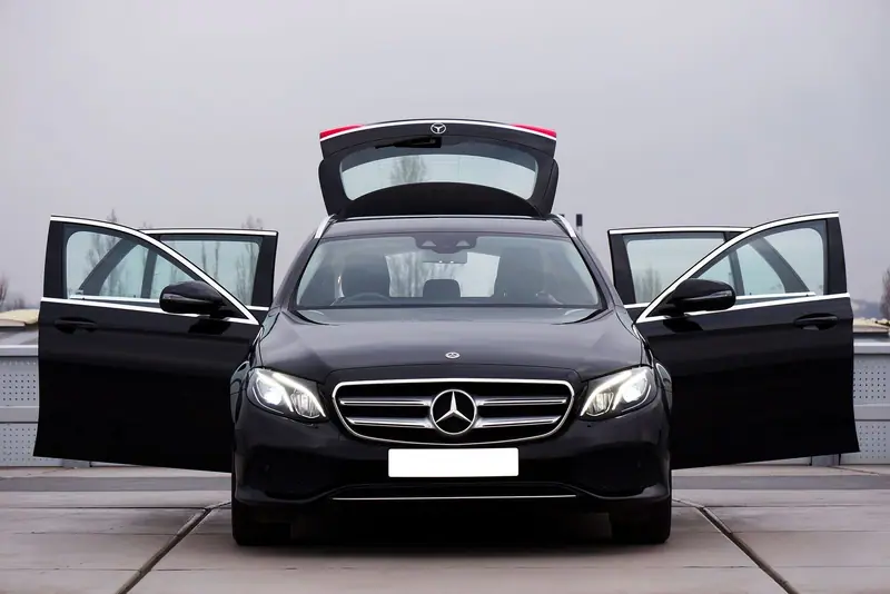 Black Mercedes-Benz E-Class seen from the front with all doors and the boot open