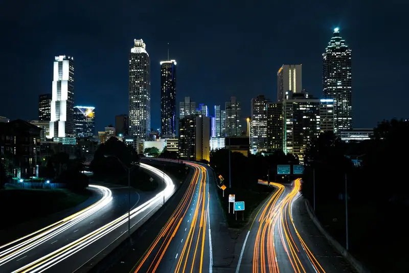 Atlanta skyline at night above a highway with light trails