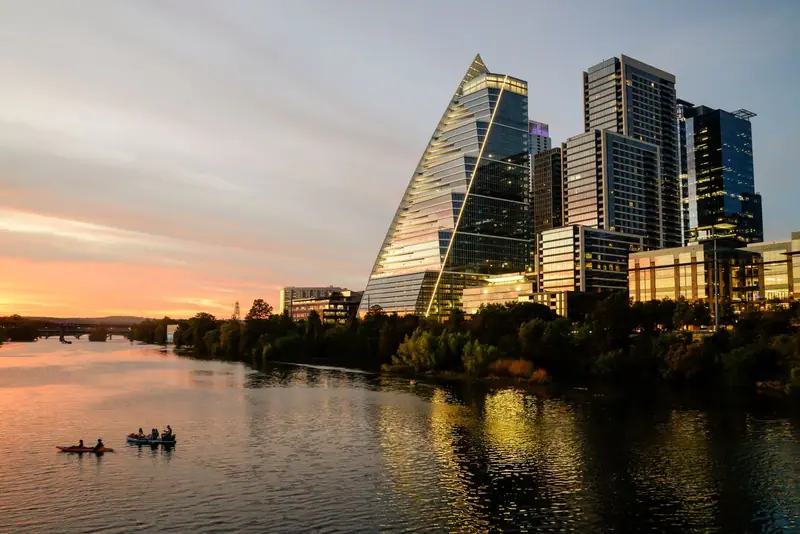 Austin skyline at sunset beside the river with two boats