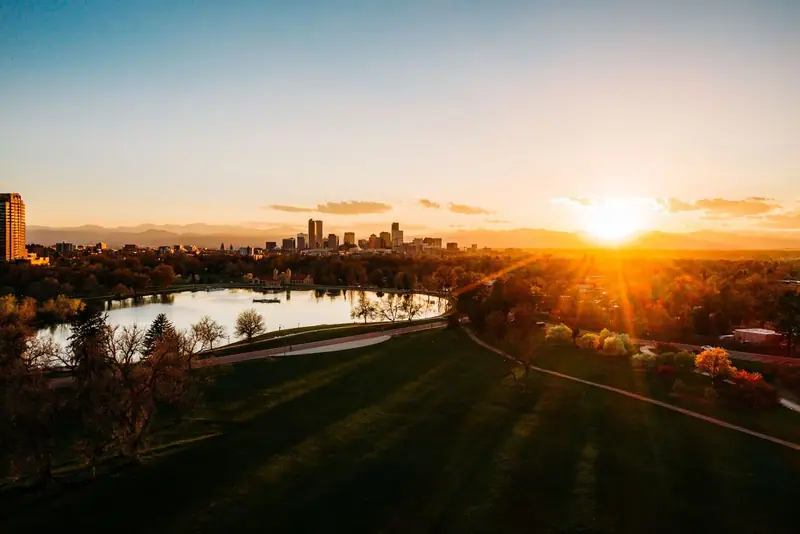 Denver skyline at sunset behind a park lake