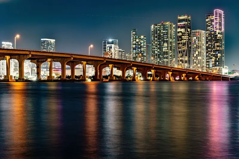 Miami skyline at night with a lit bridge over the water