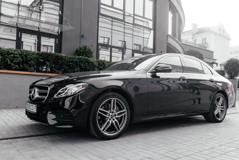 Black Mercedes-Benz E-Class sedan parked on a city street in front of a hotel